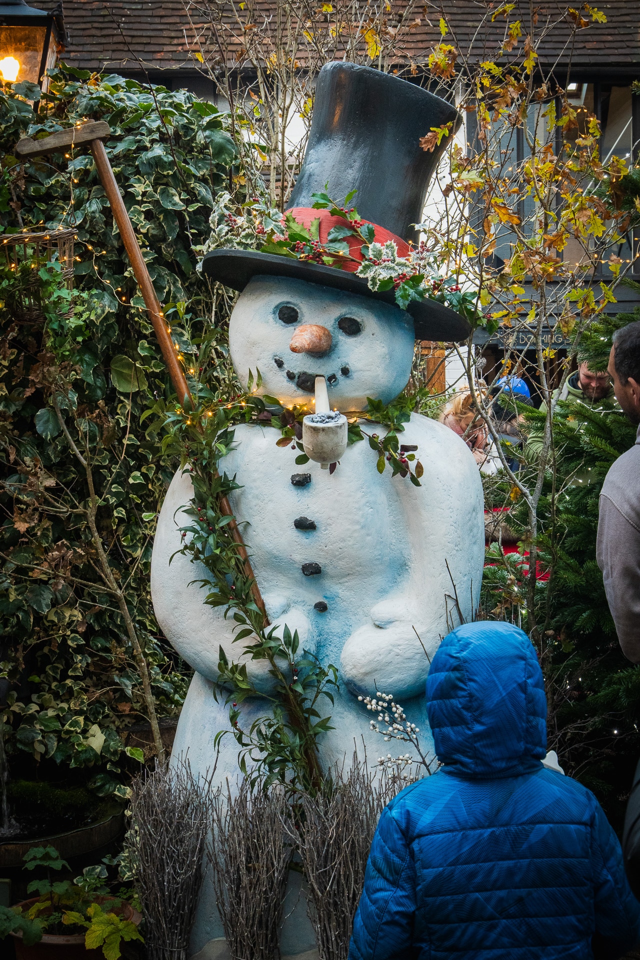 Child in blue coat looking at large snowman decoration at Dorking Christmas event