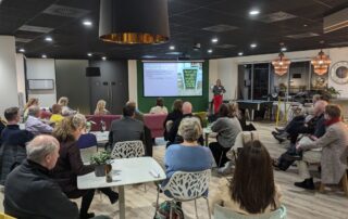Business networking event with attendees seated watching presentation in modern office space