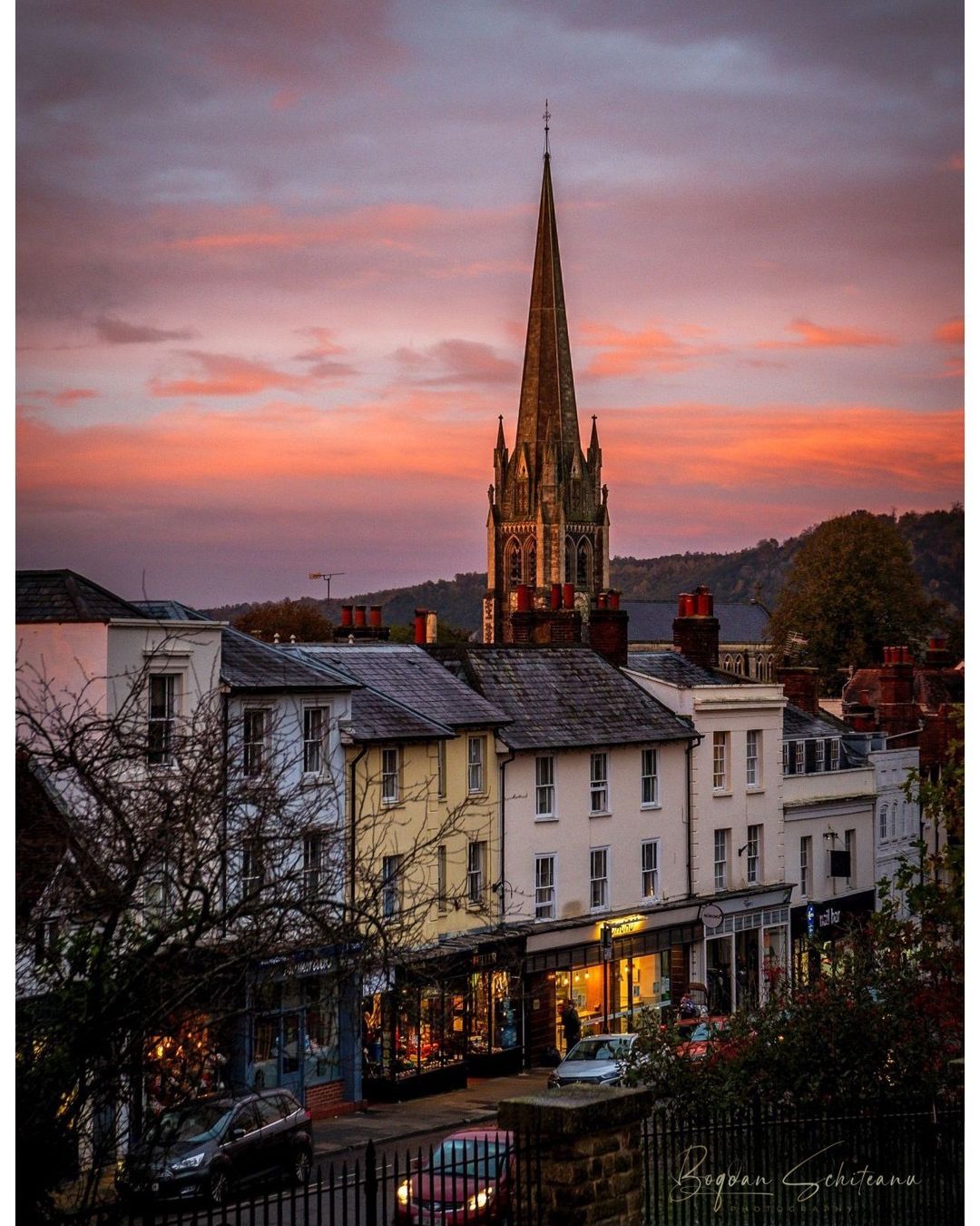 St Martin's Church spire at sunset above Dorking High Street shops with pink and orange sky