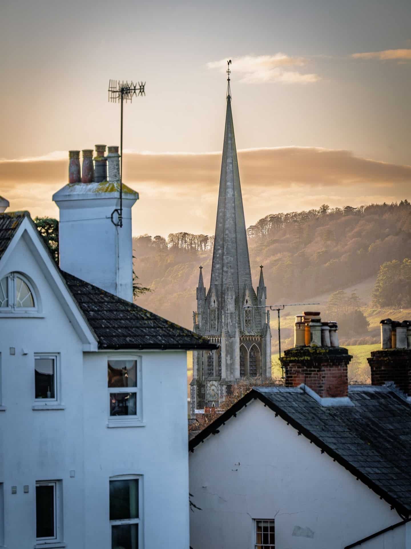 St Martin's Church spire rising above Dorking rooftops with Surrey Hills in background at golden hour