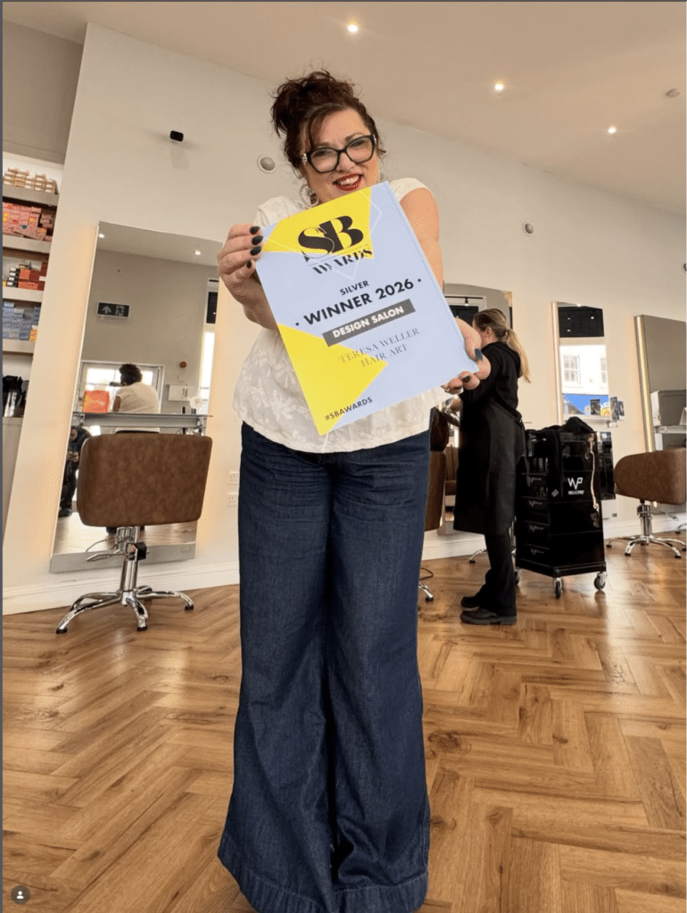 Teresa Weller holding Salon Business Awards Design Salon Silver Winner certificate inside modern salon