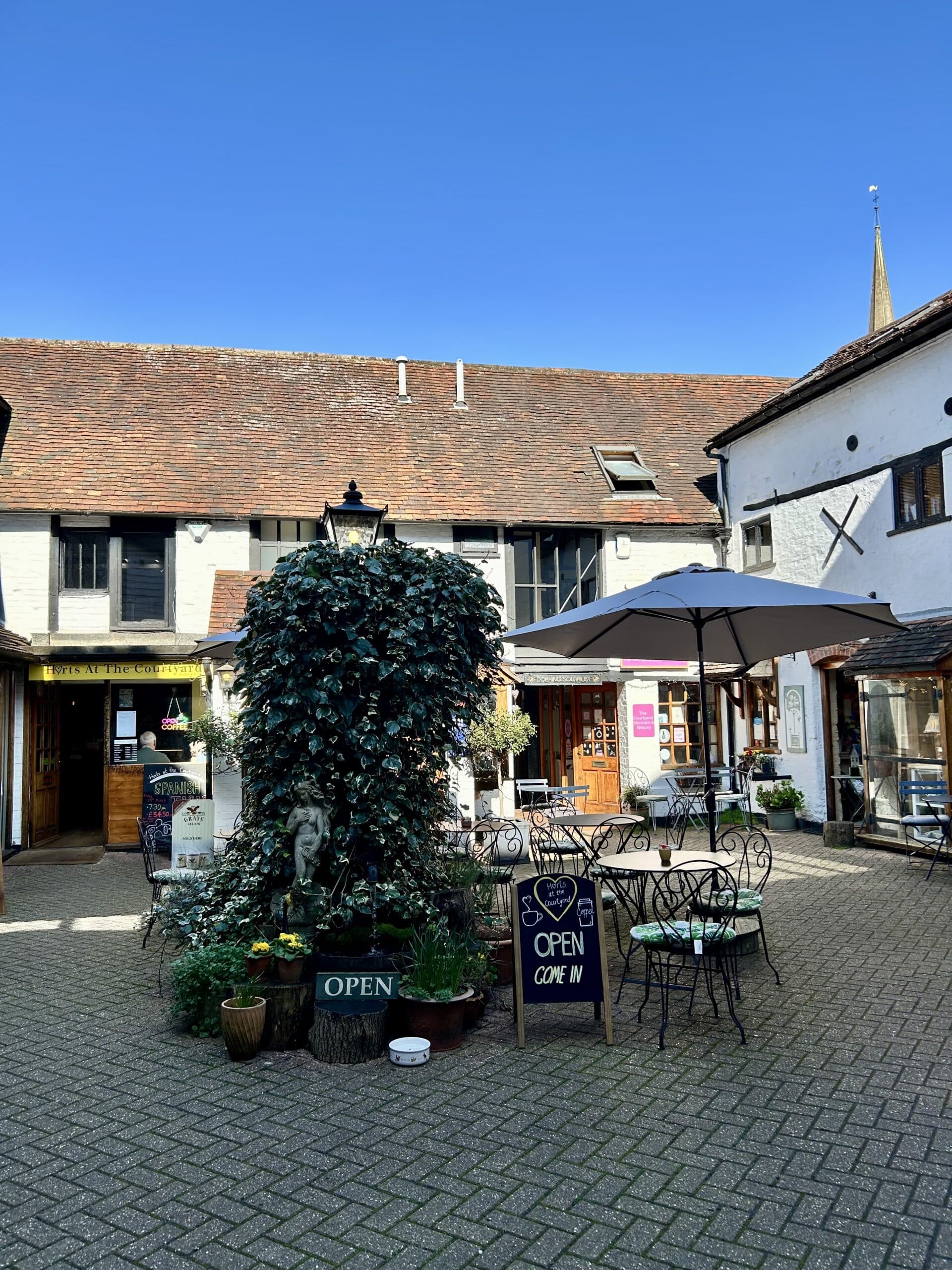 Old Kings Courtyard in Dorking with independent shops, outdoor seating, and St Martin's Church spire