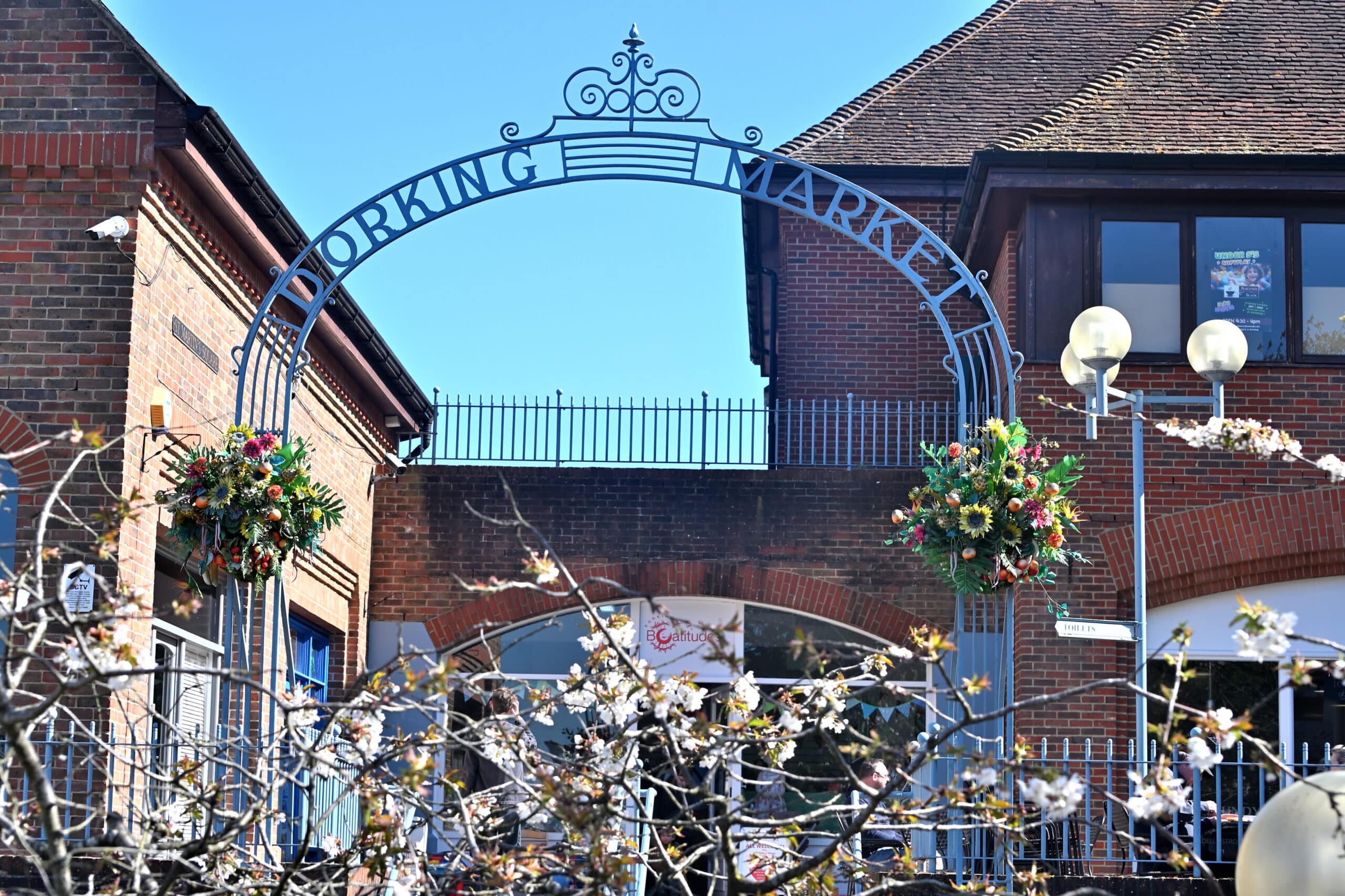 Dorking Market arch entrance with spring hanging baskets and cherry blossom