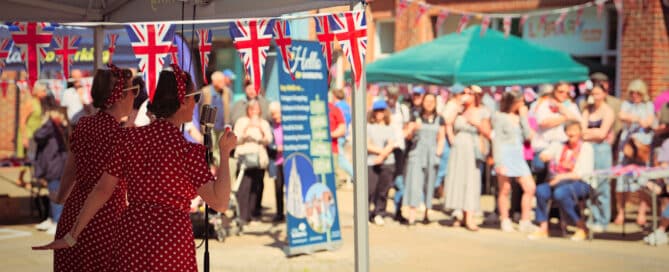 Singer in vintage 1940s dress performing at Dorking Vintage Day with Union Jack bunting and crowd