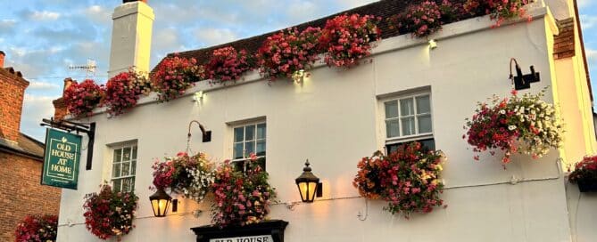 The Old House At Home pub in Dorking with red and white hanging baskets in summer