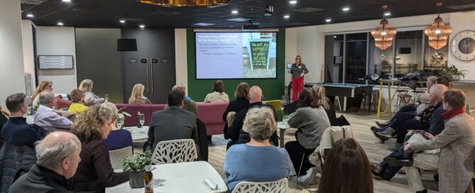 Business networking event with attendees watching presentation in modern office space